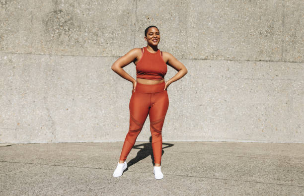здоровая женщина в спортивной одежде стоит на открытом воздухе - hand on hip стоковые фото и изображения