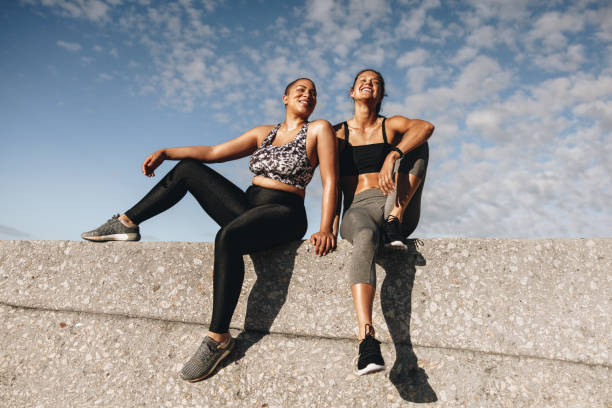 dos mujeres fitness relajándose después del entrenamiento - fitness apparel fotografías e imágenes de stock