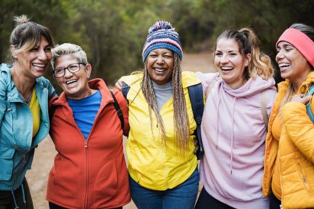 Multiracial women having fun during trekking day in to the wood - Escape to nature and travel concept stock photo