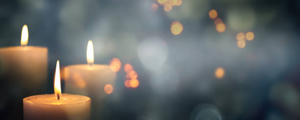 closeup of 3 burning candles on abstract black background, contemplate celebration mood with blurry lights, festive concept with copy space - advento imagens e fotografias de stock