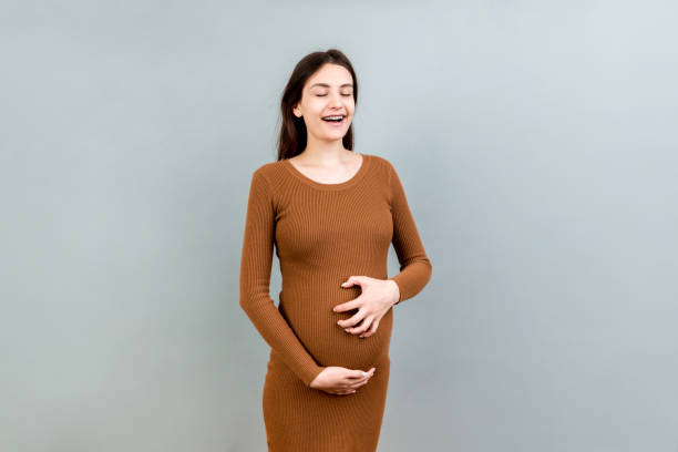 istock Pregnant woman scratching her belly on colored background 1352015396