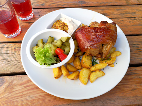 Polish cuisine - pork knuckle with potatoes, mustard and pickled cucumber
