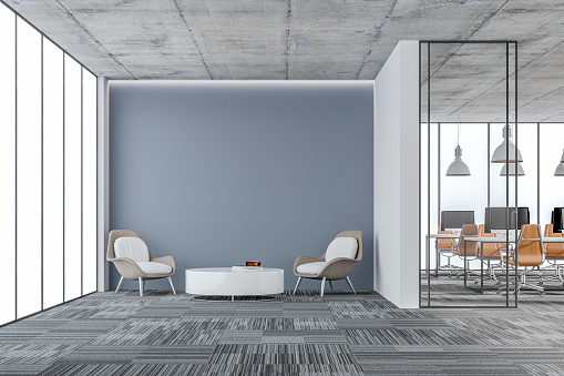 Empty office interior with a lounge corner - a table and two chairs and a large empty green plaster wall background with copy space. Wordesks, lighting and computer equipment and windows in background behind glass door on carpet floor. 3D rendered image.