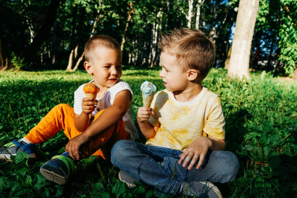 istock Kid boys eating ice cream on grass. 1352019782