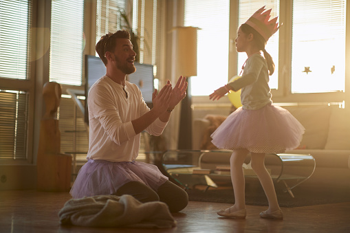 A young father enjoying a ballet training in a relaxed atmosphere at home with his little ballerina. Family, ballet, training