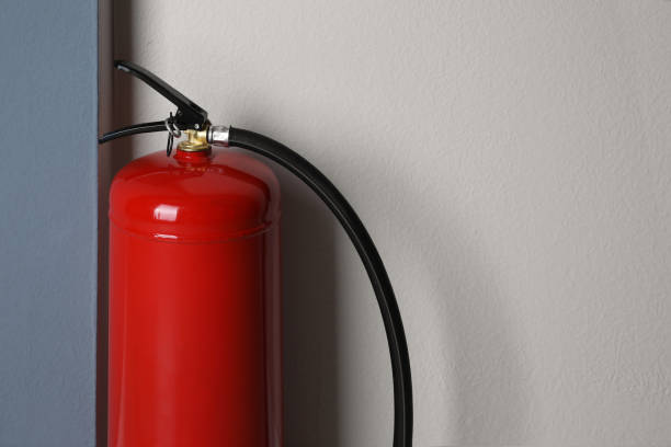 istock Fire extinguisher near light wall indoors, closeup. Space for text 1352022623