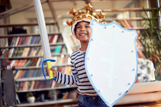 A cheerful little boy dressed as knight is posing for a photo while enjoying a playtime at home. Family, home, playtime