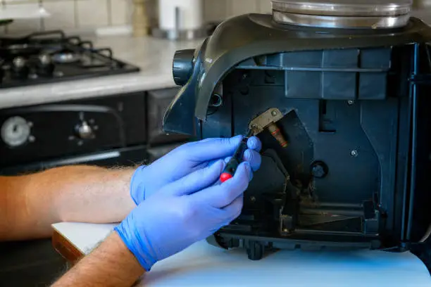 A repairman fixes a broken coffee maker, repair of household appliances