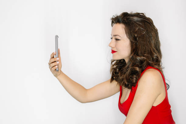 istock Smiling Young Woman Using Smart Phone Against White Background 1352029092