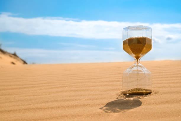istock Hourglass with flowing sand in desert on sunny day. Space for text 1352031316