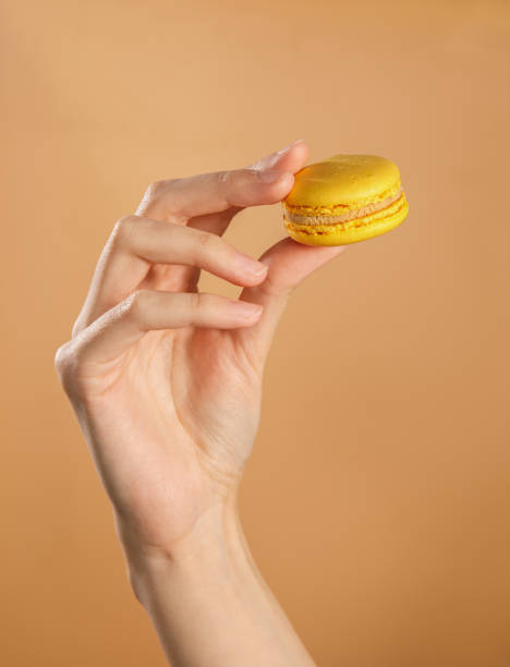 istock female hand holding yellow macaroon 1352034311