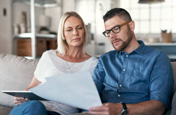 istock Shot of a couple sitting in their lounge reviewing bills while using a digital tablet 1352036724