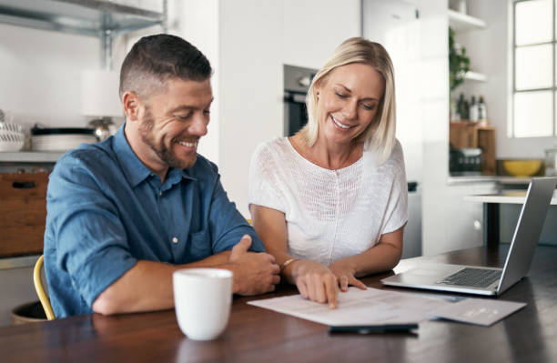 istock Shot of a couple signing documents while using their laptop in the kitchen 1352036812