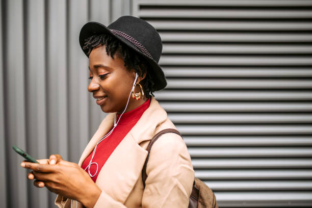 istock Busy, young woman using smart phone and earphones while walking 1352037260