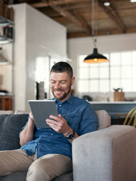 istock Shot of a handsome man relaxing on his sofa using a digital tablet 1352037799