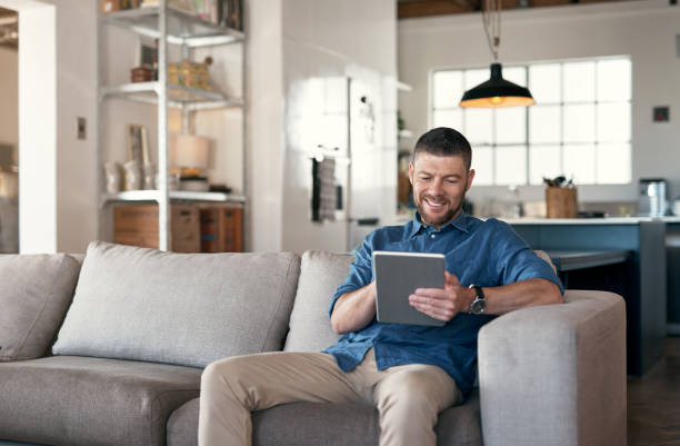 istock Shot of a handsome man relaxing on his sofa using a digital tablet 1352037816