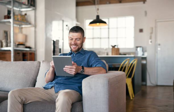Shot of a handsome man relaxing on his sofa using a digital tablet