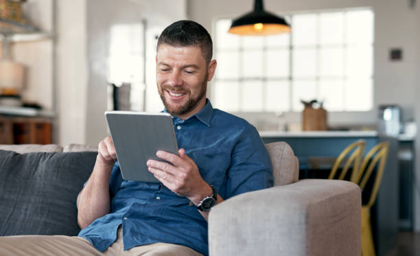 istock Shot of a handsome man relaxing on his sofa using a digital tablet 1352037866