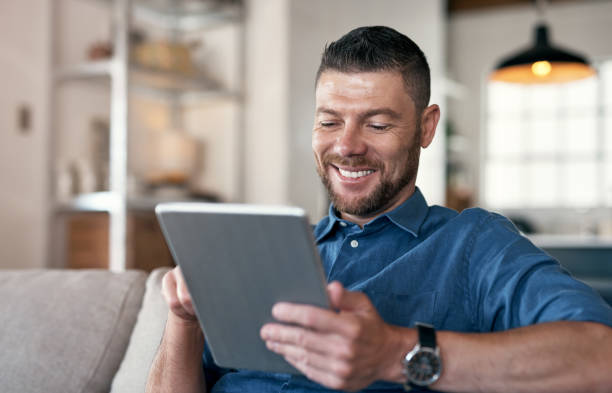 istock Shot of a handsome man relaxing on his sofa using a digital tablet 1352037874