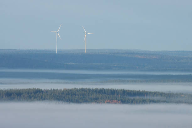 Two wind turbines working in Northern Finland during a foggy morning.
