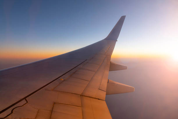 aereo che vola sopra il cielo durante il tramonto. ala dell'aereo e luce solare - wing airplane window sunset foto e immagini stock