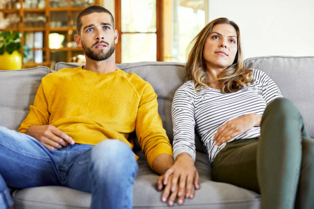 istock Couple holding hands while watching TV at home 1352043709