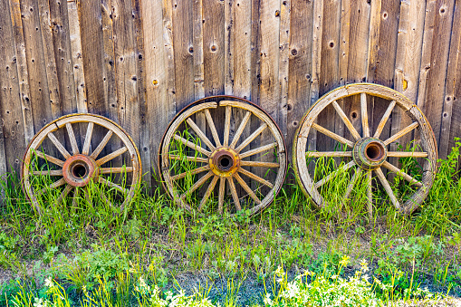 Three old weathered wooden wagon wheels against a barn wall