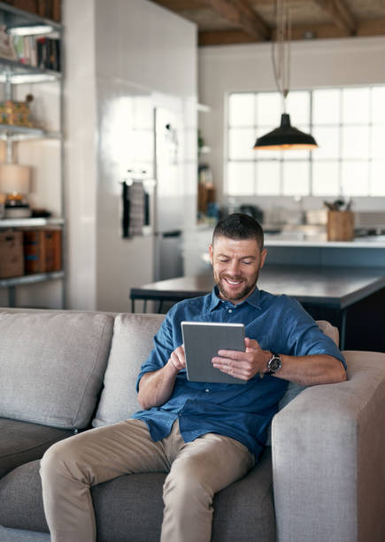 istock Shot of a handsome man relaxing on his sofa using a digital tablet 1352049029