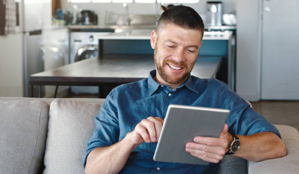 istock Shot of a handsome man relaxing on his sofa using a digital tablet 1352049036