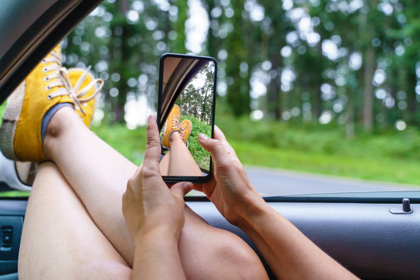 Close up with selective focus of unrecognizable woman using smartphone in a car.