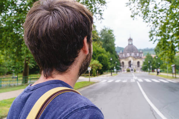 istock Unrecognizable man with backpack hiking the spanish Santiago way with religious basilica in the background. 1352049302