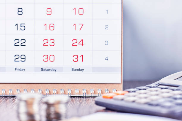 istock Calendar, calculator and stack of coins in office 1352053609