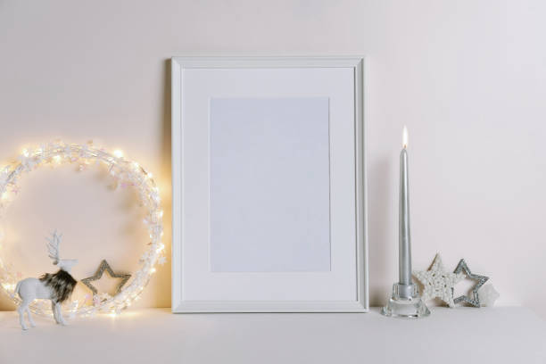 istock Mock up frame with Christmas decorations. Christmas composition with fir tree branch, deer, candle and silver stars on white background. 1352055258