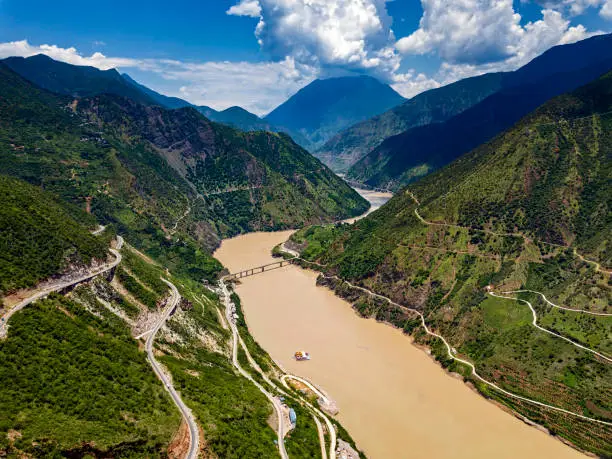 Panorama of mountains in Yunnan Province with Jinsha River and mountain roads. The Jinsha River is the Chinese name for the upper stretches of the Yangtze River. It flows through the provinces of Qinghai, Sichuan, and Yunnan in western China.