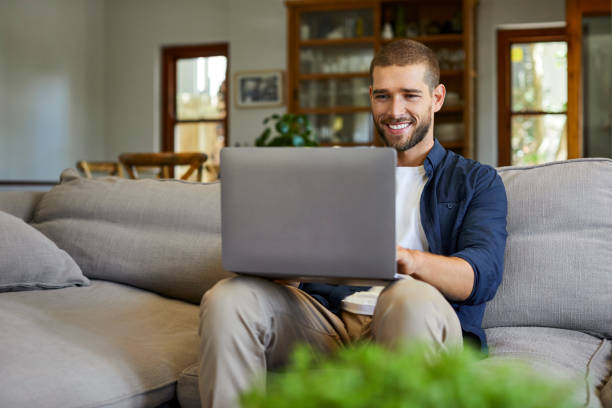 istock Happy man using laptop on sofa at home in lockdown 1352057225