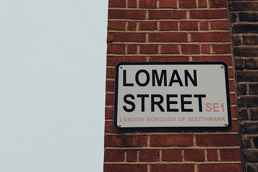 London, UK - October 17, 2021: Street name sign on Loman Street in Southwark, area that is home to London Bridge station and the attractions of The Shard, Tate Modern, and Shakespeare's Globe.