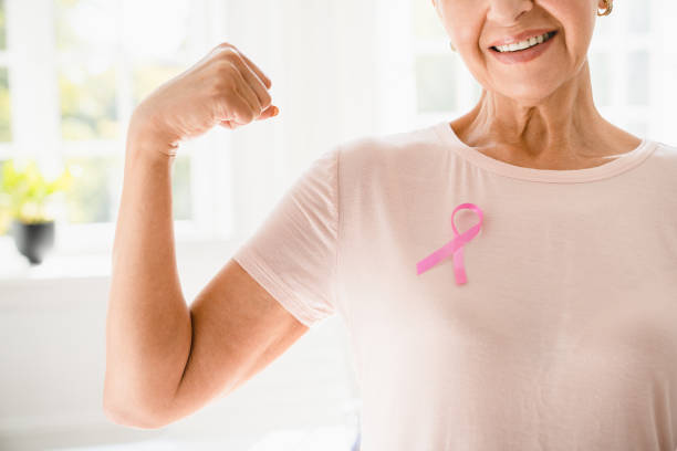 anciana anciana madura mujer fuerte con camiseta rosa con cinta rosa que apoya la lucha por el movimiento contra el cáncer de mama. unión, concepto de recuperación oncológica - breast cancer awareness fotografías e imágenes de stock
