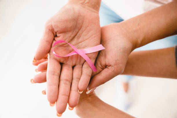 manos de mujeres sosteniendo cinta rosa en apoyo del cáncer de mama. día mundial contra el cáncer. organización benéfica, lucha contra la oncología de tumores - breast cancer awareness fotografías e imágenes de stock