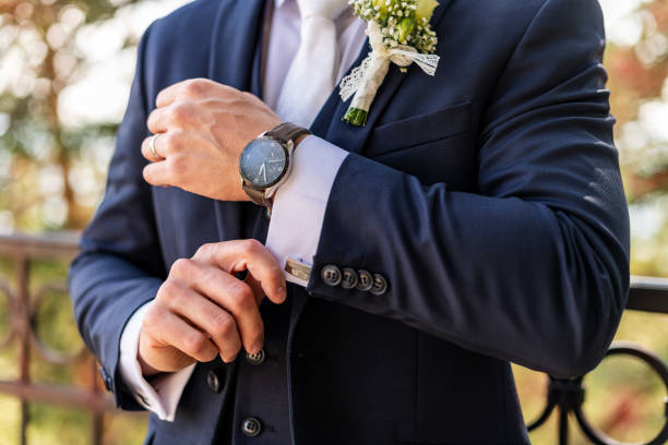 istock Groom fixing his cufflinks. Handsome groom dressed in dark blue formal suit getting ready for wedding. Elegant groom wedding fashion. 1352062324