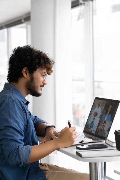 istock Focused young indian man watching lecture seminar with interracial speakers 1352062885
