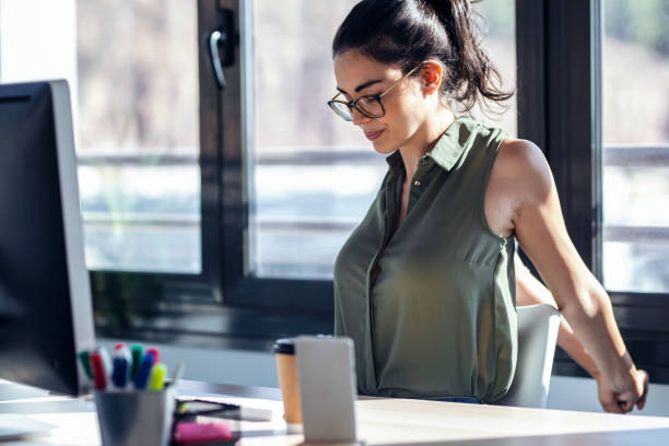 istock Tired businesswoman stretching body for relaxing while working with computer in the office. 1352063581