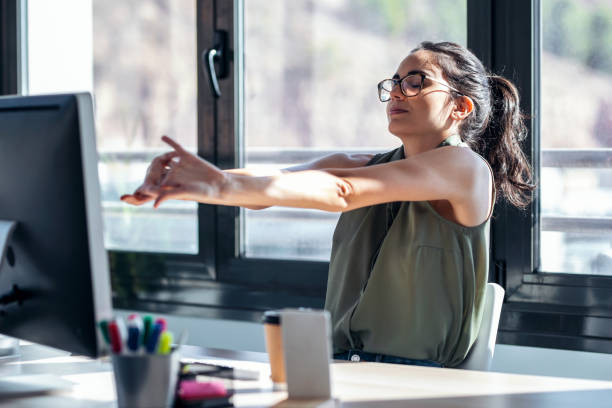 donna d'affari stanca che allunga il corpo per rilassarsi mentre lavora con il computer in ufficio. - streatching foto e immagini stock