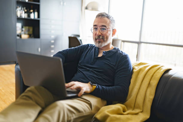 istock Portrait of handsome man with laptop on sofa 1352063874