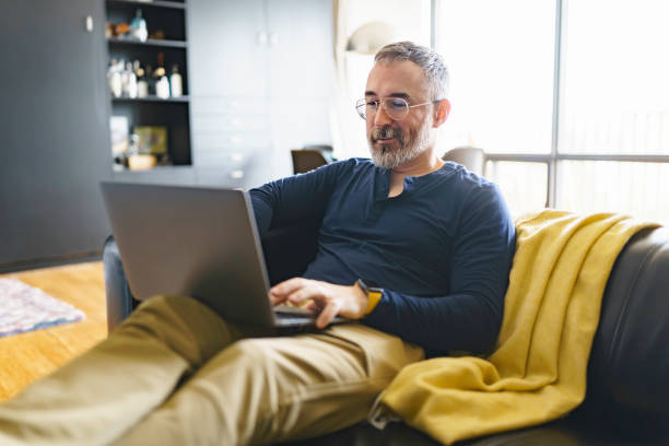 istock Portrait of handsome man with laptop on sofa 1352063879