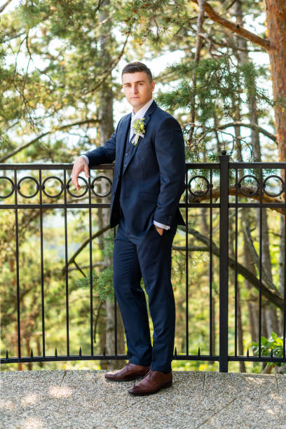 istock Handsome young groom wearing elegant dark blue suit looking at camera outdoors  portrait. Stylish groom fashion. 1352064241