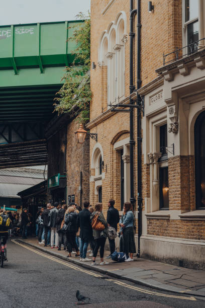 People queuing for take away food inside Borough Market, London, UK. London, UK - October 17, 2021: People queuing for take away food inside Borough Market, one of the largest and oldest food markets in London. borough market stock pictures, royalty-free photos & images