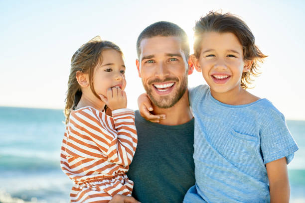istock Happy father with son and daughter at beach 1352066256