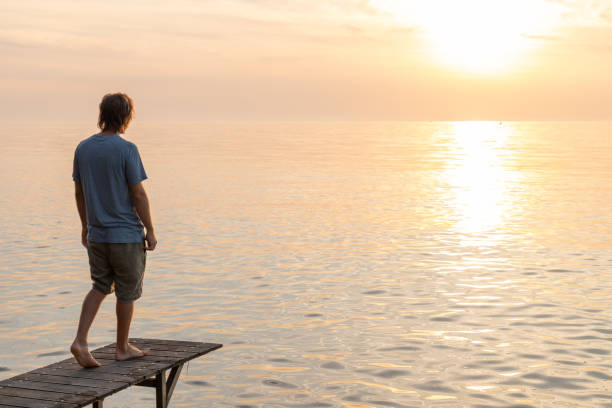 istock Young man relaxing on pier at sunset 1352071134