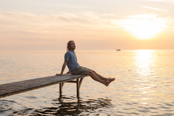 istock Young man relaxing on pier at sunset 1352071137