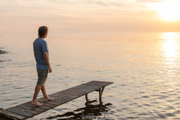 istock Young man relaxing on pier at sunset 1352071138